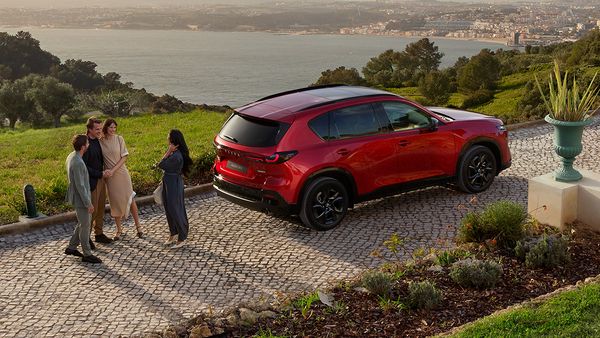 Der neue Mazda CX-5 vor einer Holzhütte.