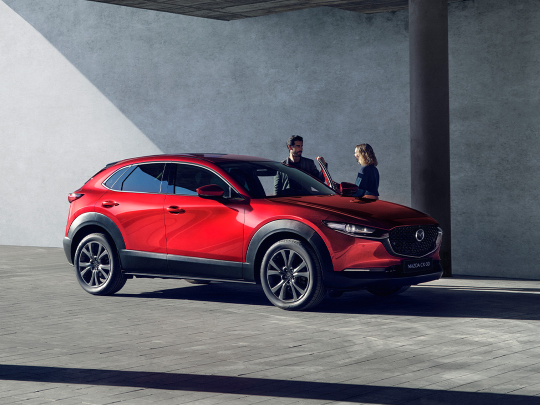 Mazda CX-30 auf einem Parkplatz mit zwei Personen um das Auto