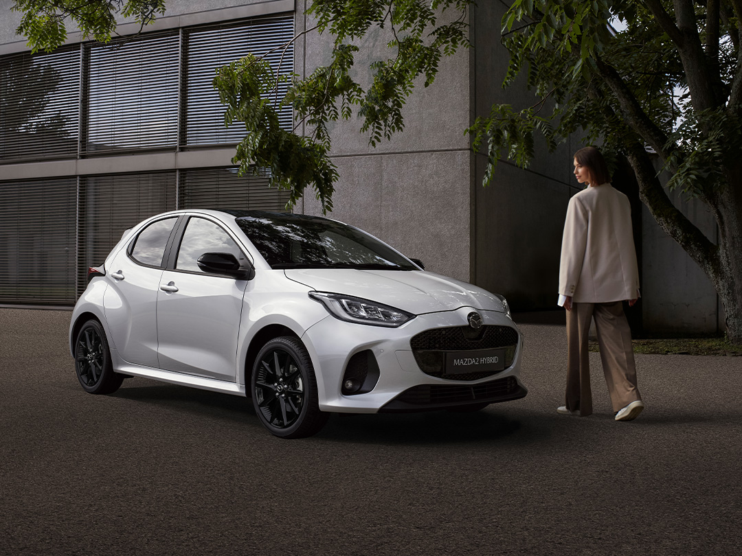 Der Mazda 2 auf eine Parkplatz vor einem modernen Gebäude