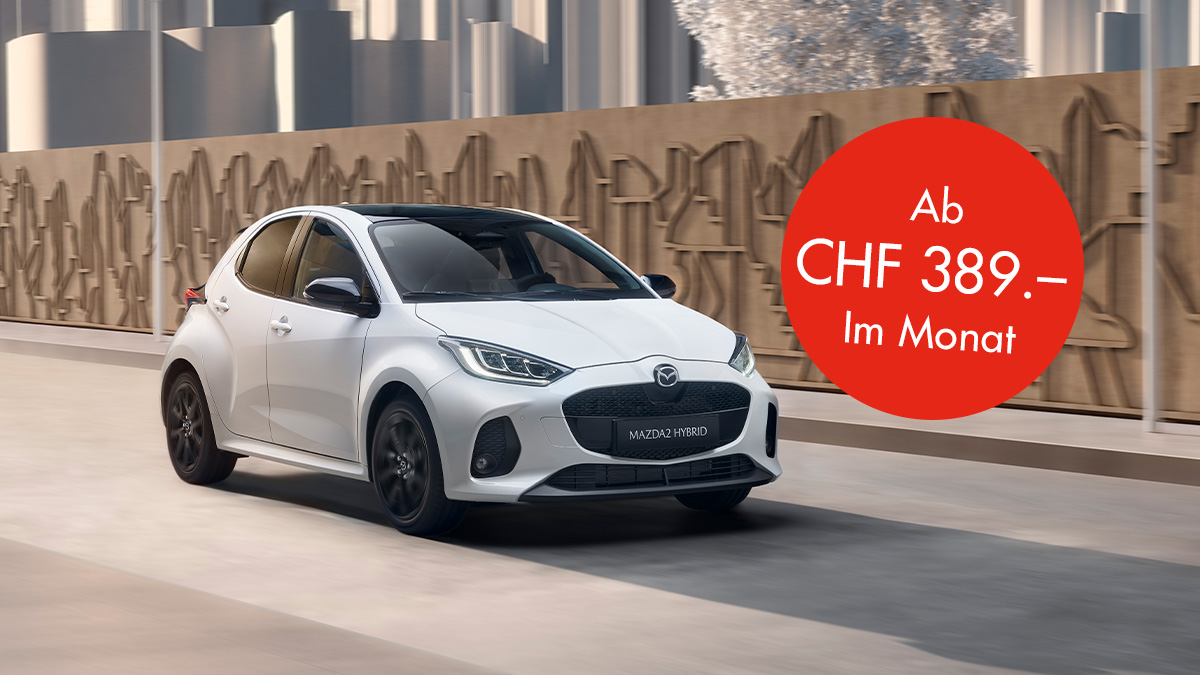 Mazda 2 Hybrid auf einer Strasse vor einer Wand mit einem Störer auf dem Bild